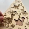 Détail Puzzle en bois - Les dinosaures une pièce tenue en main