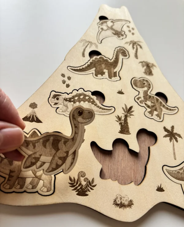 Détail Puzzle en bois - Les dinosaures une pièce tenue en main