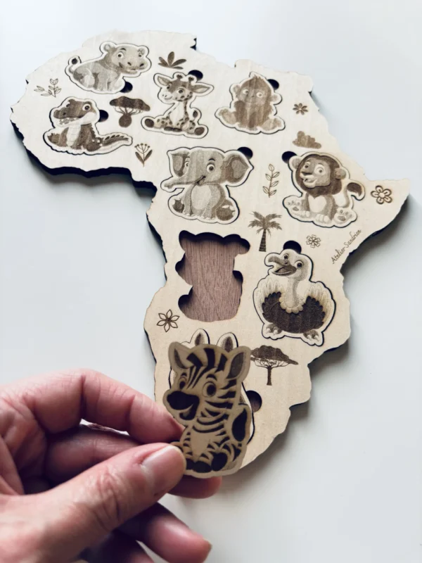 Puzzle en bois - Les animaux de l'Afrique sur la carte de l'Afrique - le zèbre tenue en main