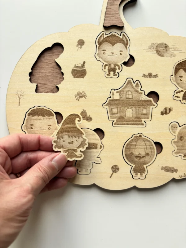 Puzzle en bois en forme de citrouille Halloween - la sorcière tenue en main