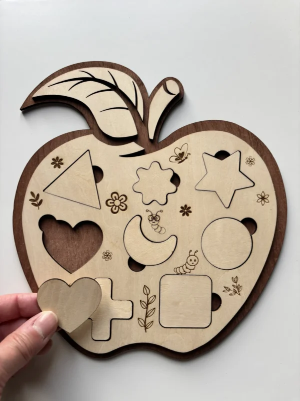 Puzzle en bois - Pomme - pièces en forme géométriques avec la pièce coeur tenue en main