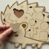 Puzzle en bois - Hérisson avec des pièces en formes géométriques dont le coeur tenu en main