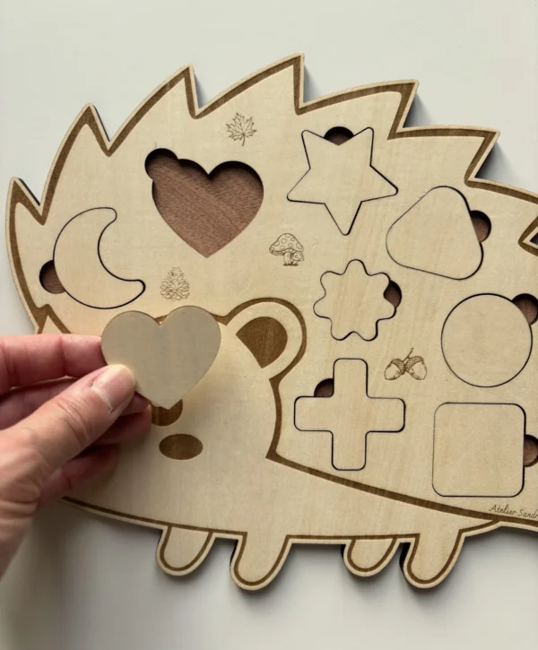 Puzzle en bois - Hérisson avec des pièces en formes géométriques dont le coeur tenu en main