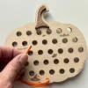 citrouille à lacer en bois - lacet orange tenu en main