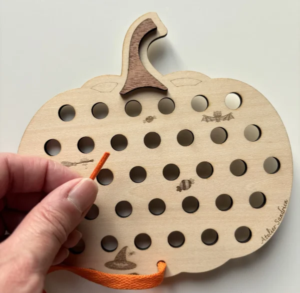 citrouille à lacer en bois - lacet orange tenu en main