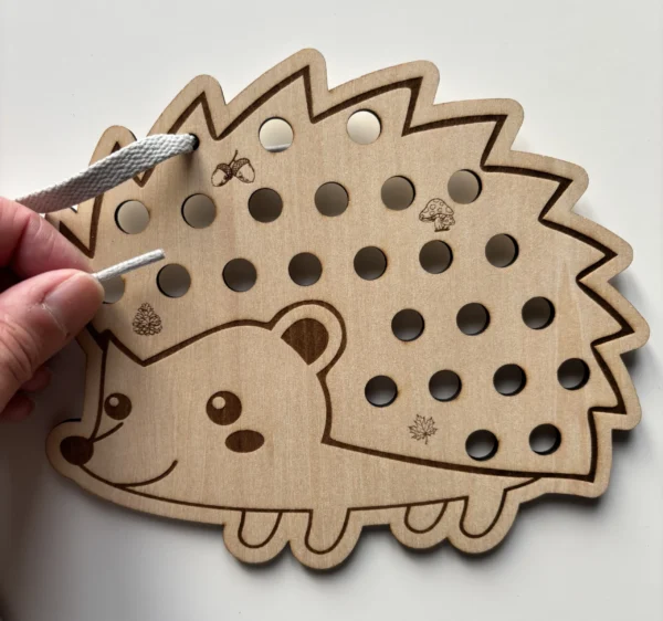 Détail hérisson en bois à lacer avec lacet gris tenu en main