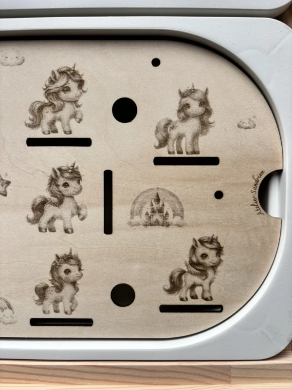 Détail d’un insert sensoriel en bois avec licornes gravées pour activité de motricité fine