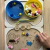 Insert sensoriel en bois autonomie aux toilettes accessoires colorés dans bols main d'enfant qui joue