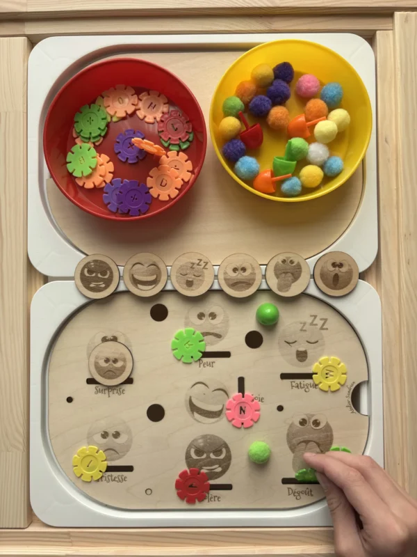 Insert sensoriel en bois les émotions accessoires colorés dans bols et accessoires posés et main d'enfant