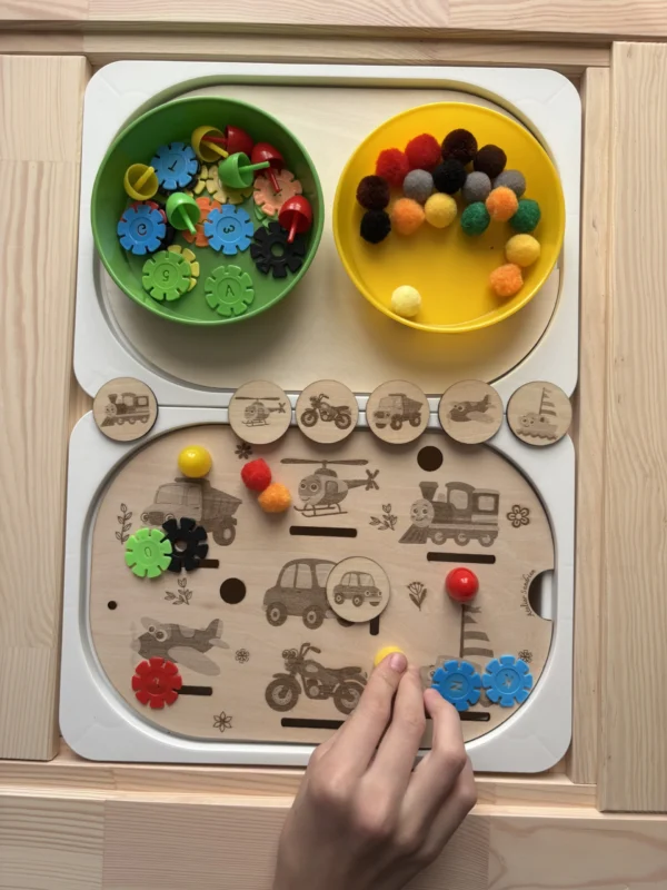 Insert sensoriel en bois avec véhicules gravés, jetons ronds et accessoires colorés et main d'enfant qui joue