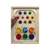 Insert sensoriel en bois - Atelier des couleurs et ses gobelets remplis de pompons de couleurs avec une main d'enfant