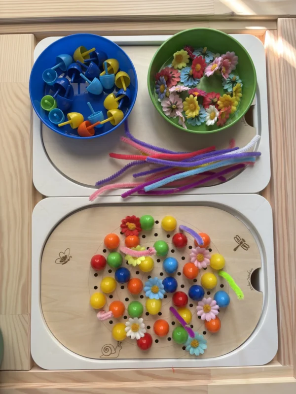 Insert sensoriel en bois spirale avec différents accessoires posés et déposés dans deux bols