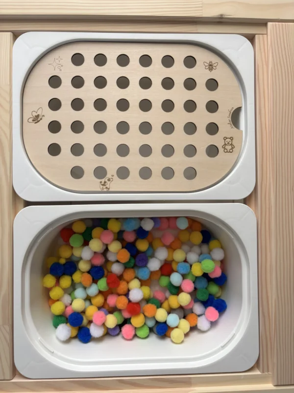 Insert sensoriel en bois avec trous pompons de 20 mm avec un bac rempli de pompons