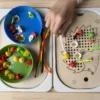 insert sensoriel en bois hérisson à petits trous avec chenilles et fleurs et bols accessoires et une main d'enfant qui joue