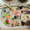 Main d’enfant qui place un jeton dans l'insert insert sensoriel légumes en bois