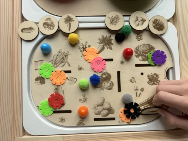 Main d’enfant qui place un jeton dans l'insert insert sensoriel légumes en bois