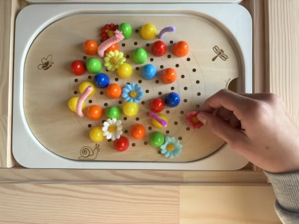 Insert sensoriel en bois spirale avec différents accessoires et une main d'enfant