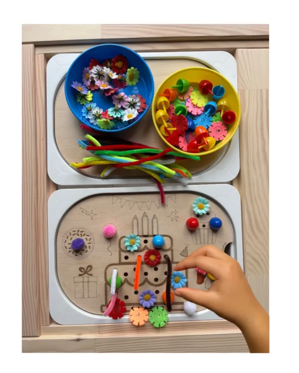 Main d’enfant plaçant une fleur sur un insert sensoriel gâteau d’anniversaire en bois