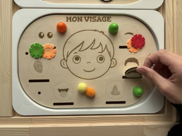 Insert sensoriel en bois le visage accessoires colorés dans bols main d'enfant qui joue