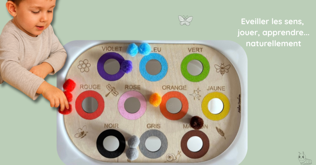 Enfant jouant avec un insert sensoriel en bois présentant les couleurs, avec pompons et anneaux colorés, pour développer la motricité fine et l’apprentissage des couleurs