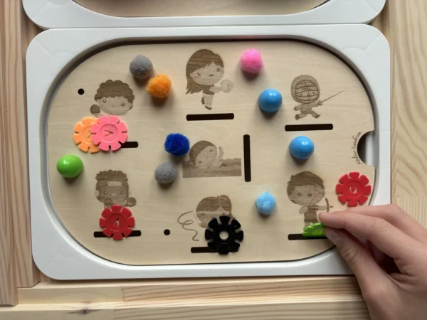 Enfant manipulant un insert sensoriel en bois thème différents sports avec pompons et jetons colorés