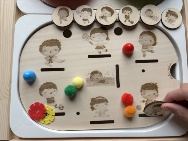 Main d’enfant utilisant un insert sensoriel sport en bois avec jetons et pompons
