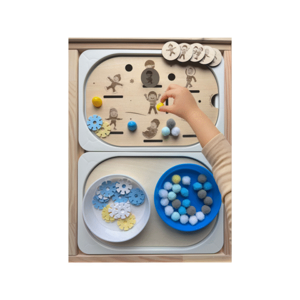 Main d’enfant manipulant un insert sensoriel Personnages d’hiver en bois avec pompons et jetons pour motricité fine