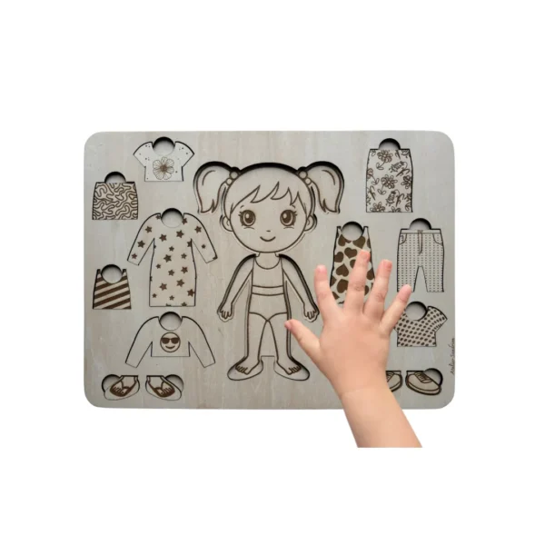 Main d’enfant manipulant un jeu de poupée à habiller en bois avec vêtements