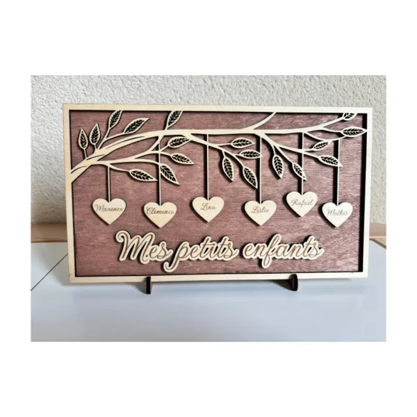 Arbre généalogique rectangulaire en bois foncé posé sur un meuble, avec cœurs suspendus personnalisés