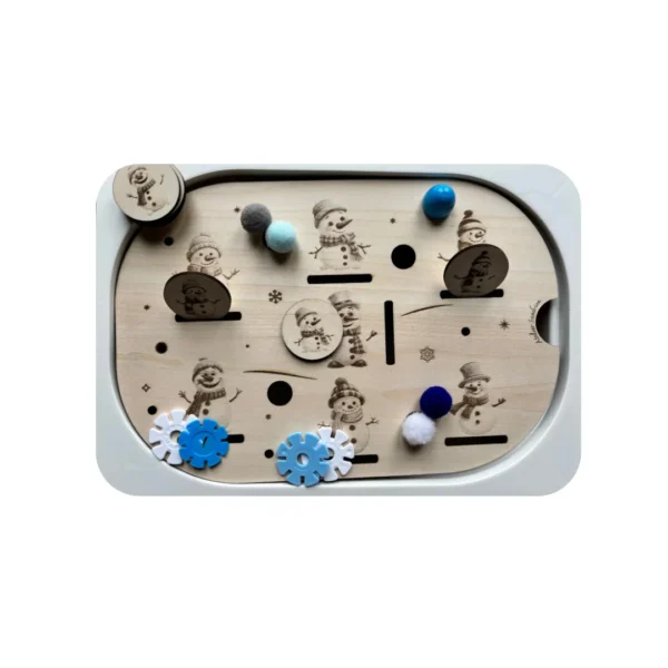 Insert sensoriel en bois thème bonhommes de neige, utilisé avec des jetons, pompons et engrenages pour une activité de motricité fine et de manipulation.
