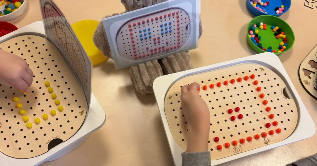 Enfant manipulant un insert sensoriel en bois lors d'un atelier, répétition de gestes de motricité fine