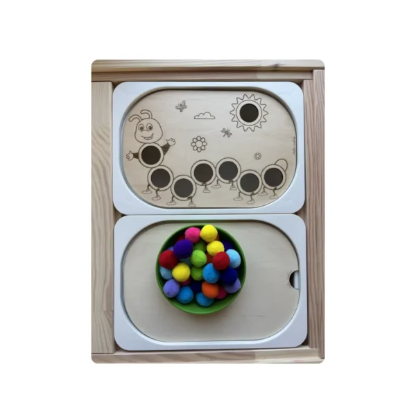 Bol rempli de pompons colorés à côté de l’insert sensoriel chenille en bois pour activité de tri et motricité fine