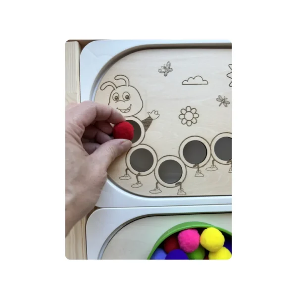 Main d’enfant insérant un pompon dans un trou de 3 cm de l’insert sensoriel chenille en bois