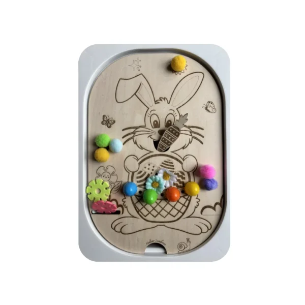 Insert sensoriel en bois thème lapin de Pâques avec pompons colorés et accessoires, permettant le tri, la manipulation et le développement de la motricité fine chez l’enfant.