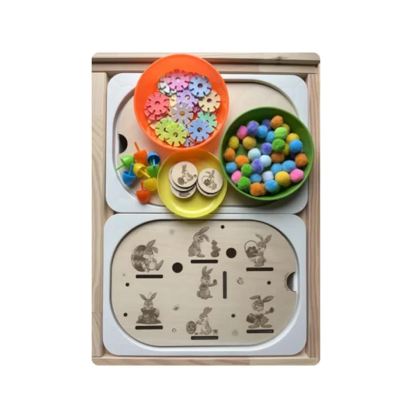 Insert sensoriel en bois thème Pâques avec lapins gravés et accessoires colorés présentés en bols pour activité de tri et motricité fine chez l’enfant.