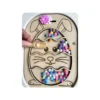 Insert sensoriel en bois thème Pâques en forme d’œuf avec lapin, utilisé pour remplir et manipuler des pompons colorés, activité favorisant la motricité fine, la coordination œil-main et l’autonomie des jeunes enfants.