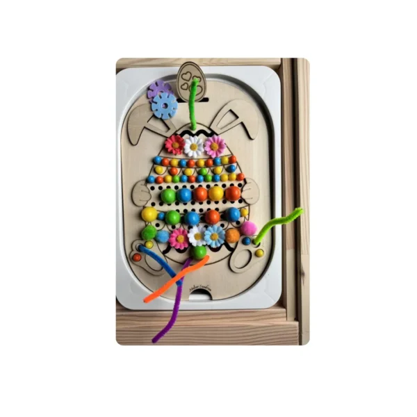 Insert sensoriel en bois thème Pâques représentant un œuf décoré avec perles colorées, fleurs et chenilles, activité éducative favorisant la motricité fine, la coordination et la créativité chez l’enfant.