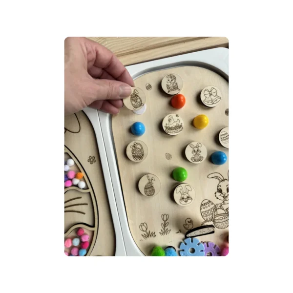 Main positionnant un jeton illustré sur un insert sensoriel en bois thème Pâques, activité éducative favorisant la motricité fine, la coordination et l’autonomie chez l’enfant.