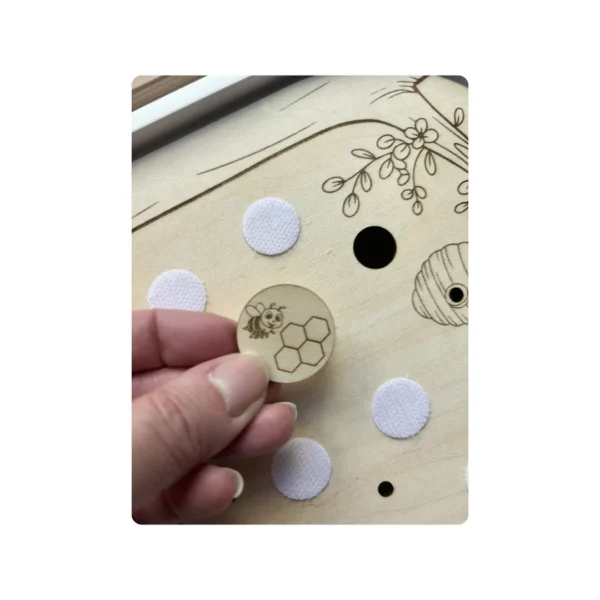Insert sensoriel en bois - Scratch thème abeille- zoom sur un jeton en bois tenu en main