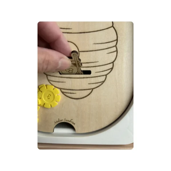 insert sensoriel en bois - zoom ruche avec main tenant un jeton en bois