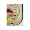 insert sensoriel en bois - zoom ruche avec main tenant une fleur plate jaune
